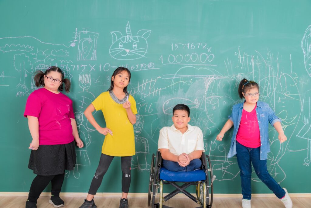 Group of young Asian disabled child student standing in front of chalkboard in element classroom